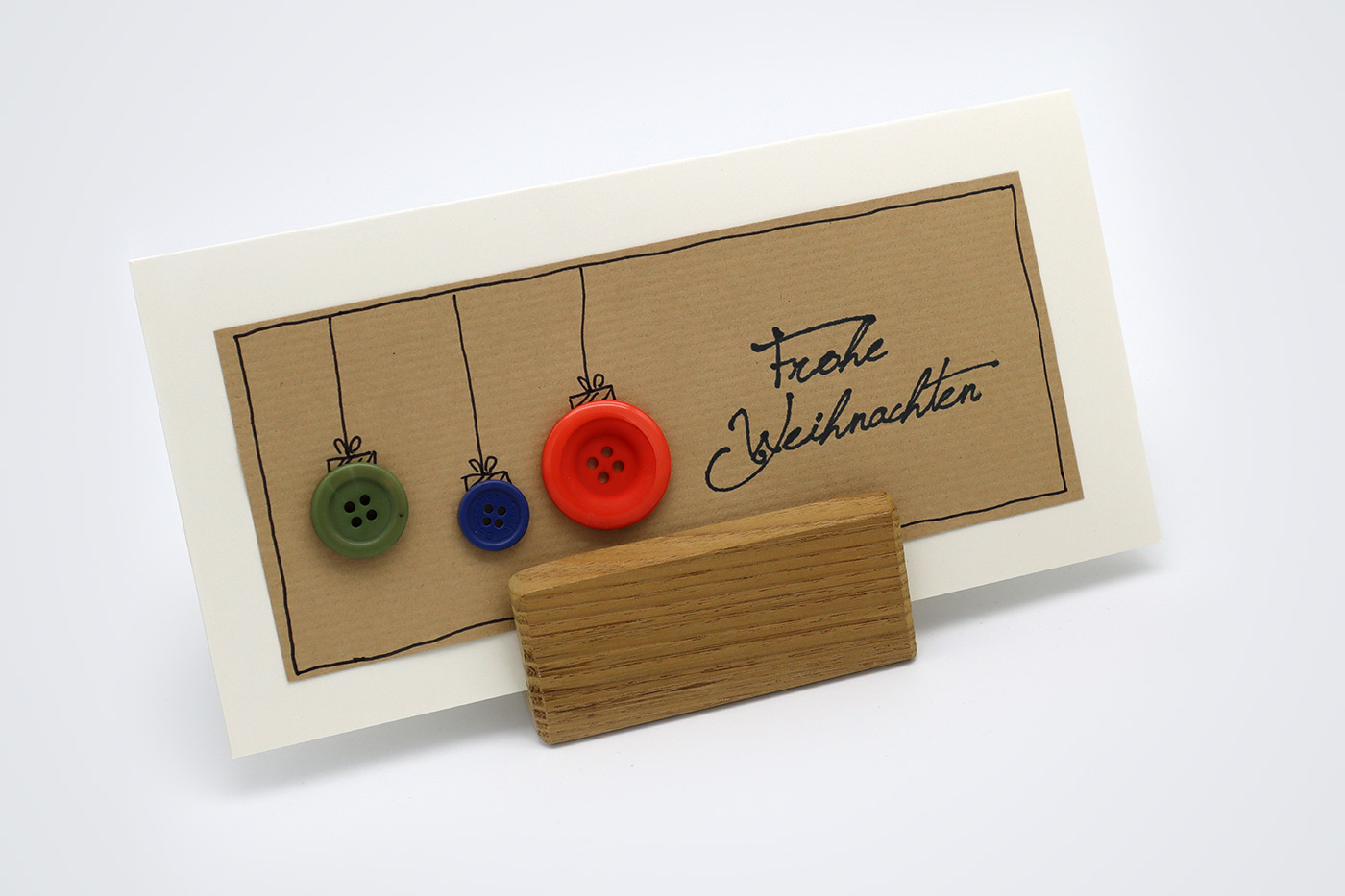 Karte mit drei bunten Knöpfen und Stempelaufdruck Frohe Weihnachten